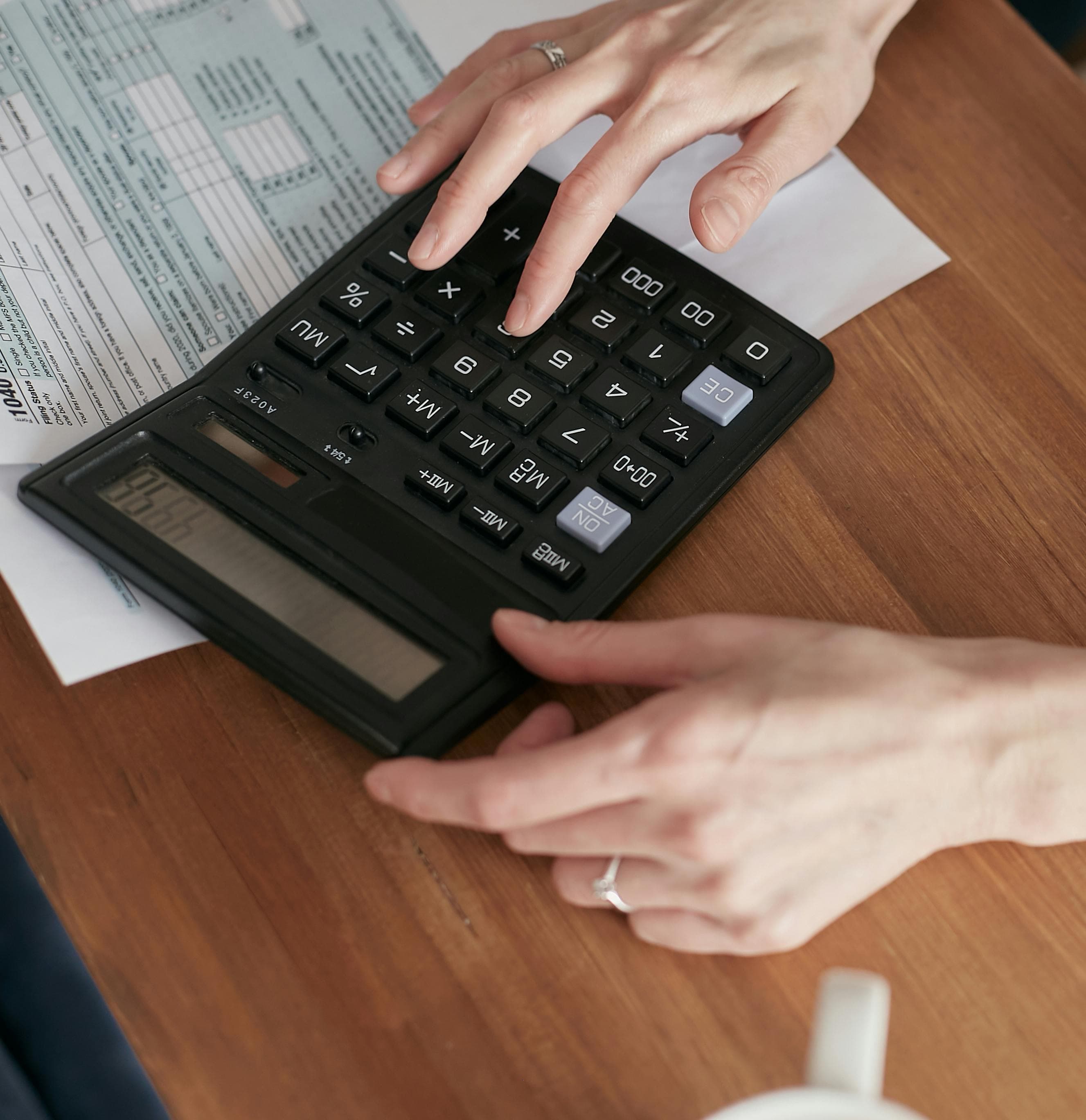 Hand using calculator to determine house cleaning pricing