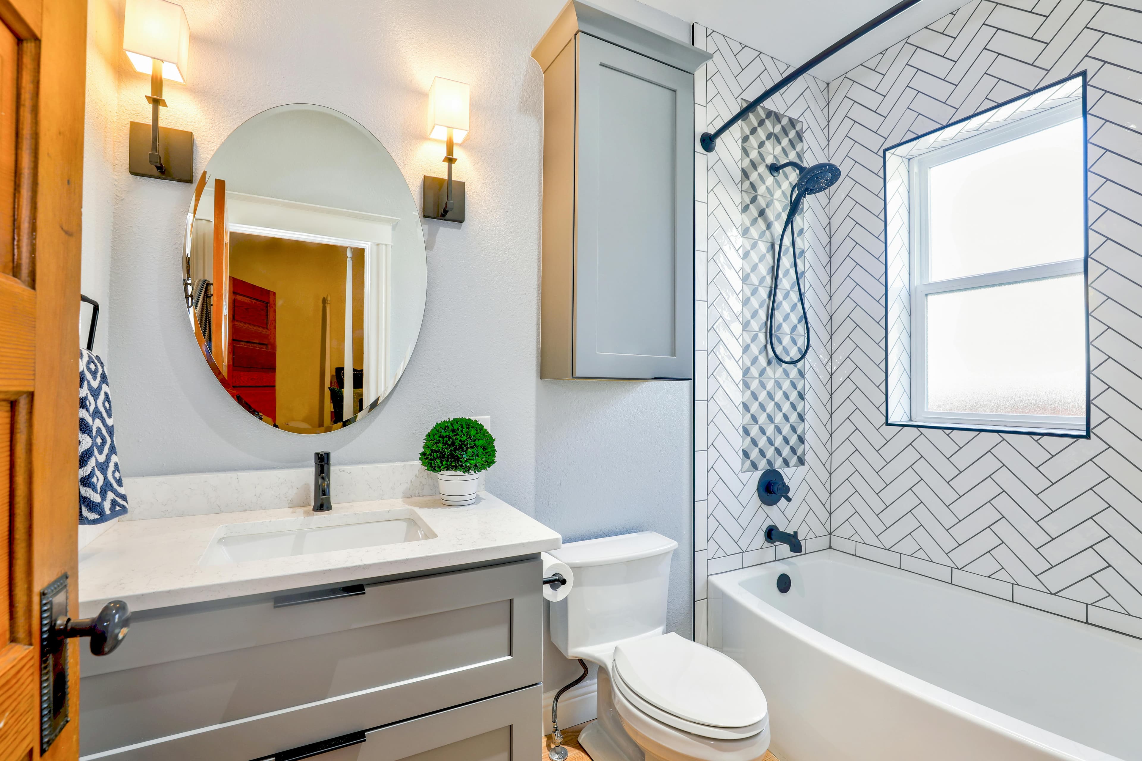 Spotless modern bathroom with white tile shower and oval mirror