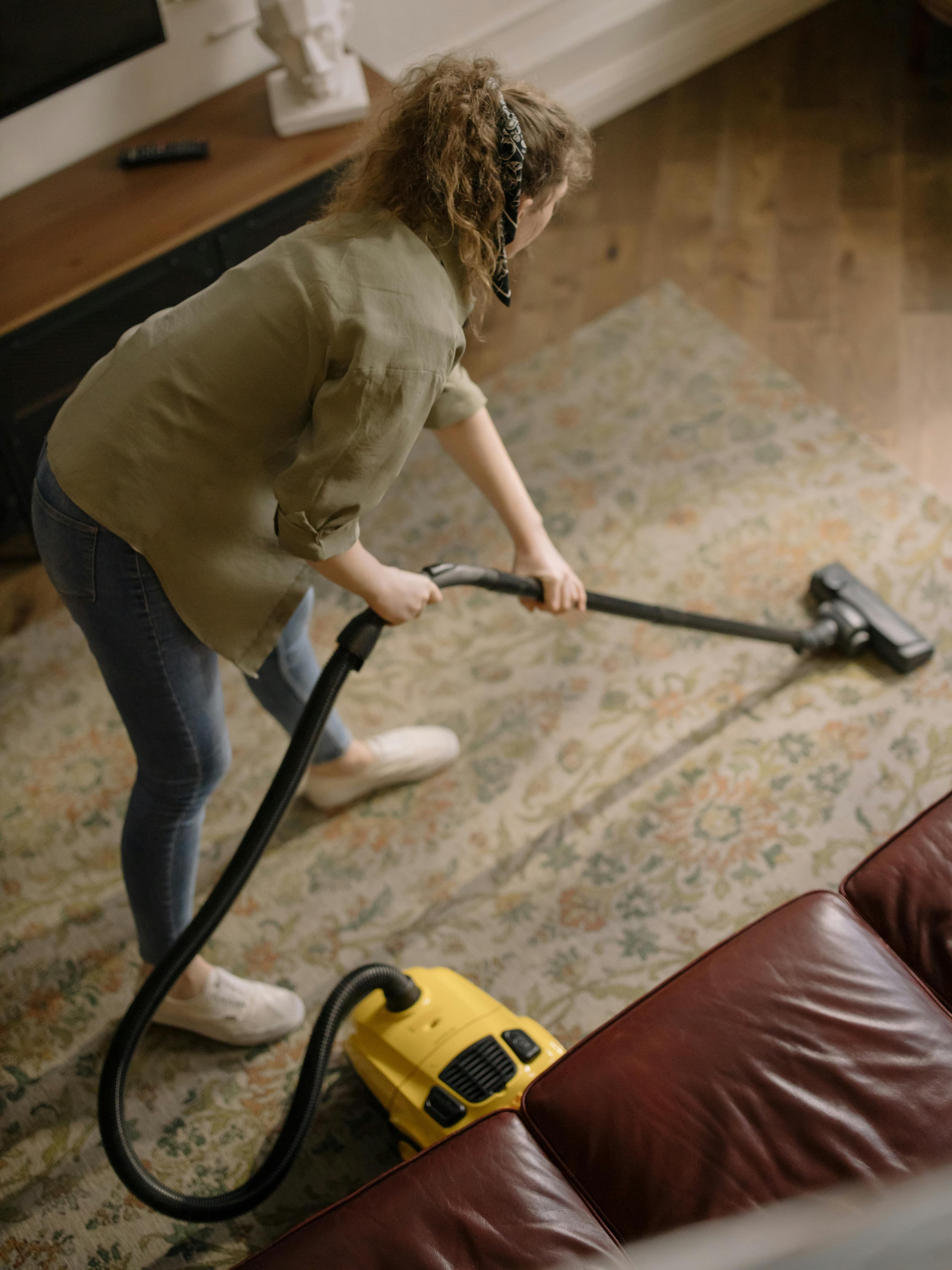 Professional cleaner vacuuming living room with area rug and furniture